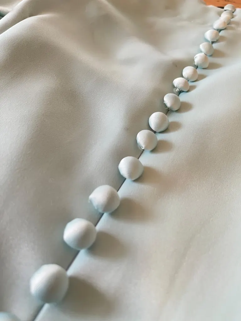 A row of fabric-covered buttons down the back of a gown